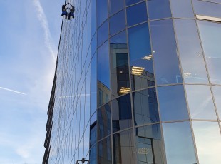 pracownik alpinistyczny myje okna